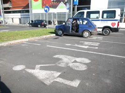 Sceny na parkingu pod supermarketem. Ciężarna zaparkowała na miejscu dla rodziny z dziećmi