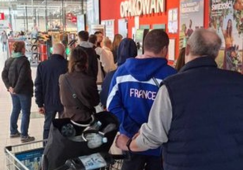 Kolejka ludzi z butelkami do zwrotu. 