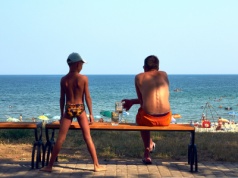 Wakacje, dzieci i rodzic z piwkiem nad wodą. 