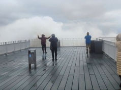 Wiatr, wzburzone morze i zadowoleni turyści z aparatami