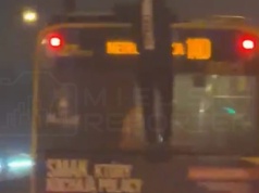 Młody mężczyzna trzymał się tyłu jadącego autobusu, następnie wspiął się i chodził po dachu